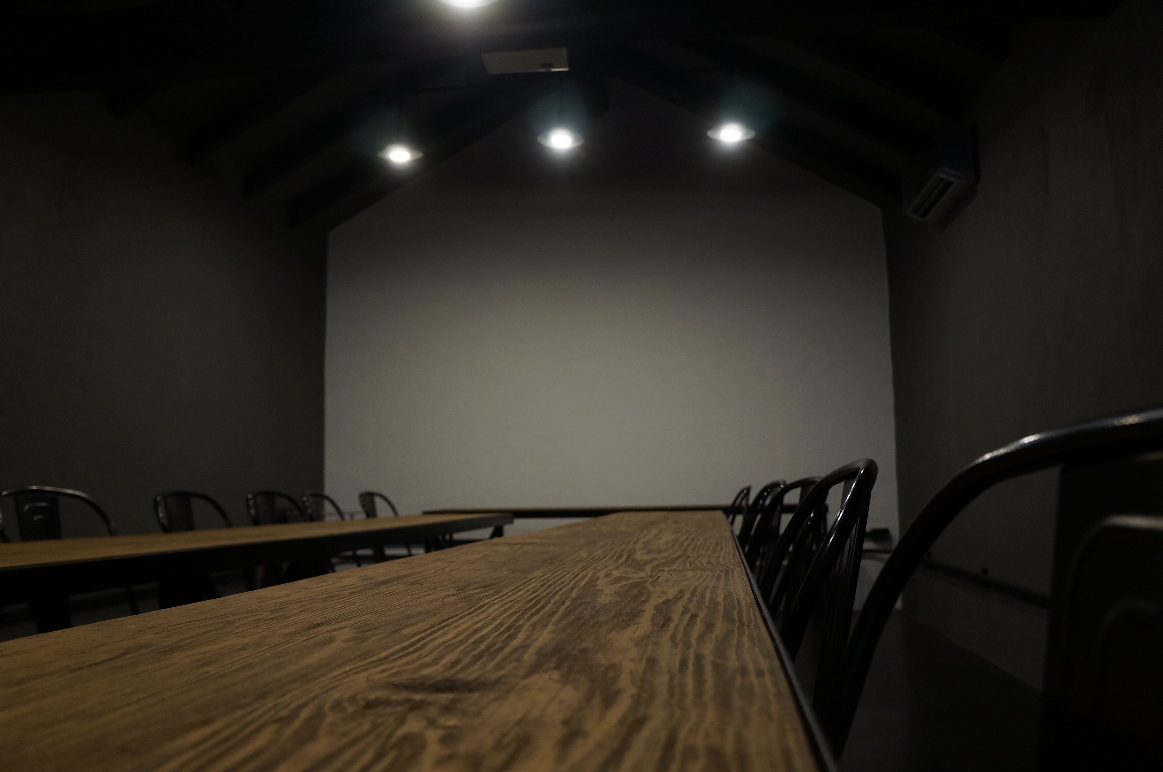 A conference room with a long wooden table, several chairs, and a large blank screen at the front.