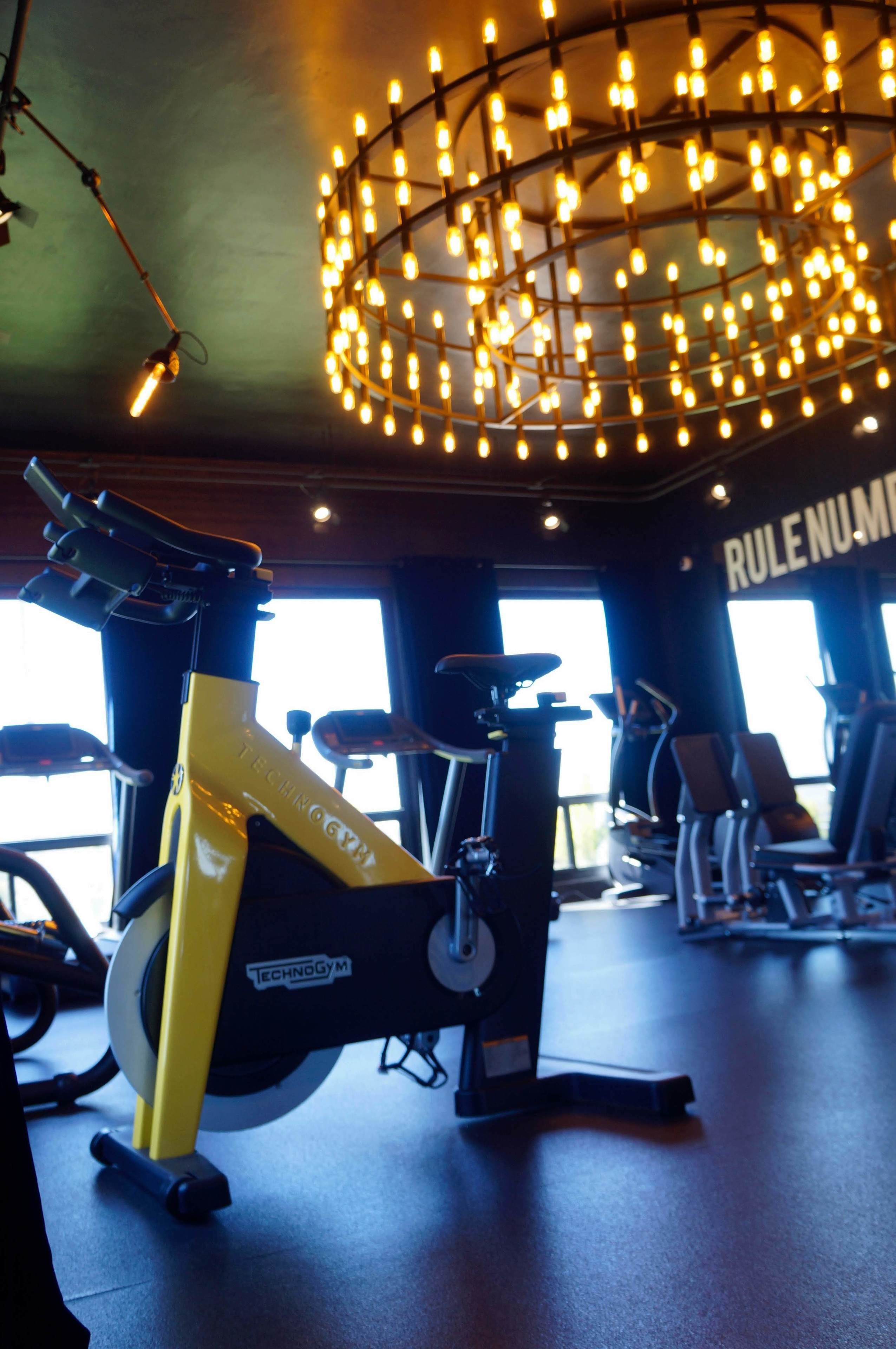 Un gimnasio con bicicletas estáticas, una lámpara en el techo y una ventana con vistas.