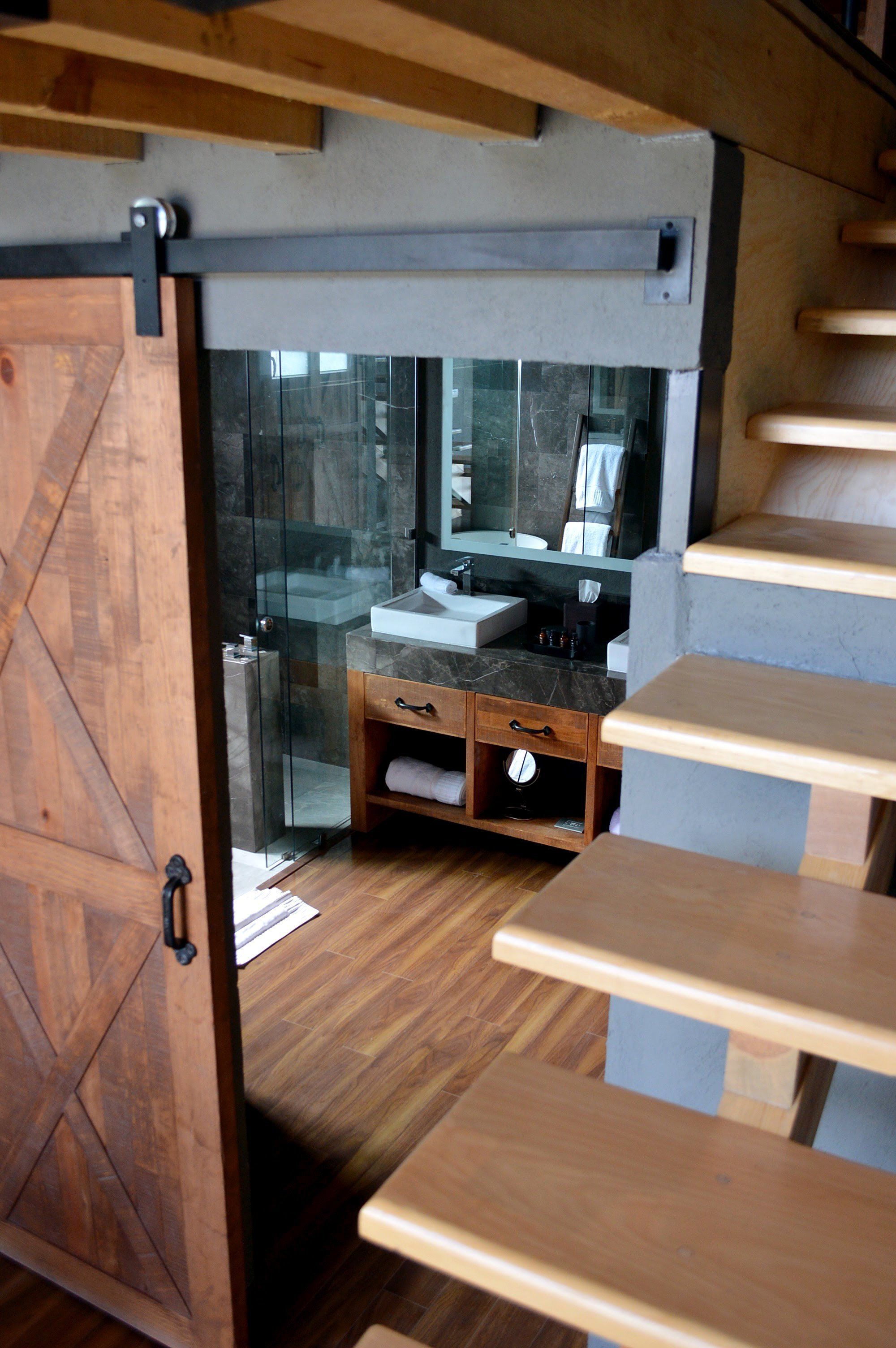 A modern bathroom with a glass shower, wooden vanity, and a large mirror.
