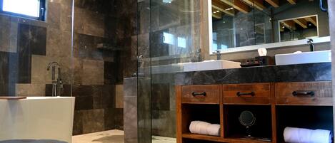 A modern bathroom with a glass-enclosed shower, a wooden vanity with a mirror, and a large mirror above the sink.