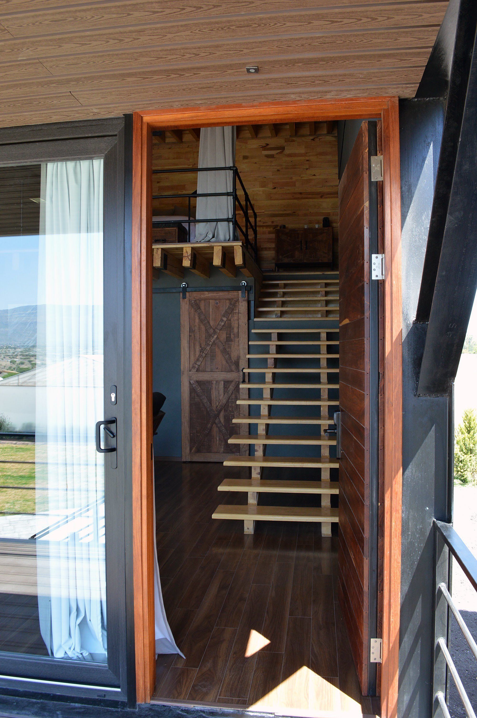 A wooden interior with a staircase leading to a loft area.