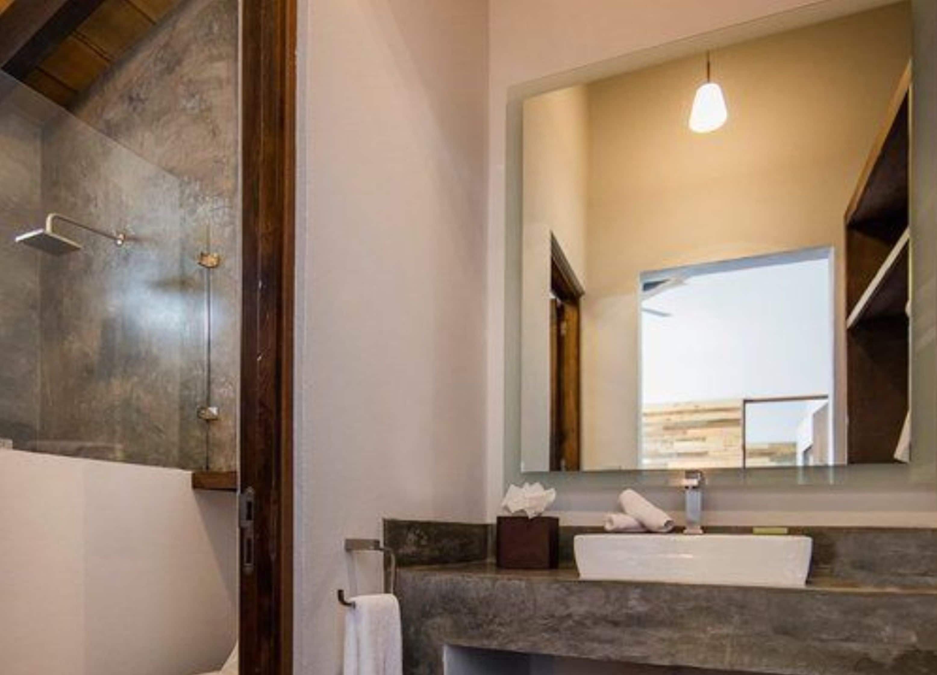 A bathroom with a large mirror, a towel rack, a sink, and a shower area.