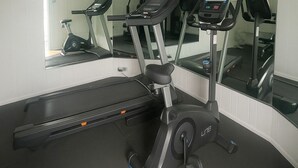 Un gimnasio con cintas de correr, una bicicleta estática y una máquina de remo.