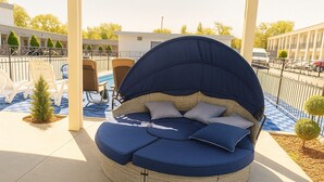 Un área de estar al aire libre circular con toldo, asientos acolchados y una mesita.