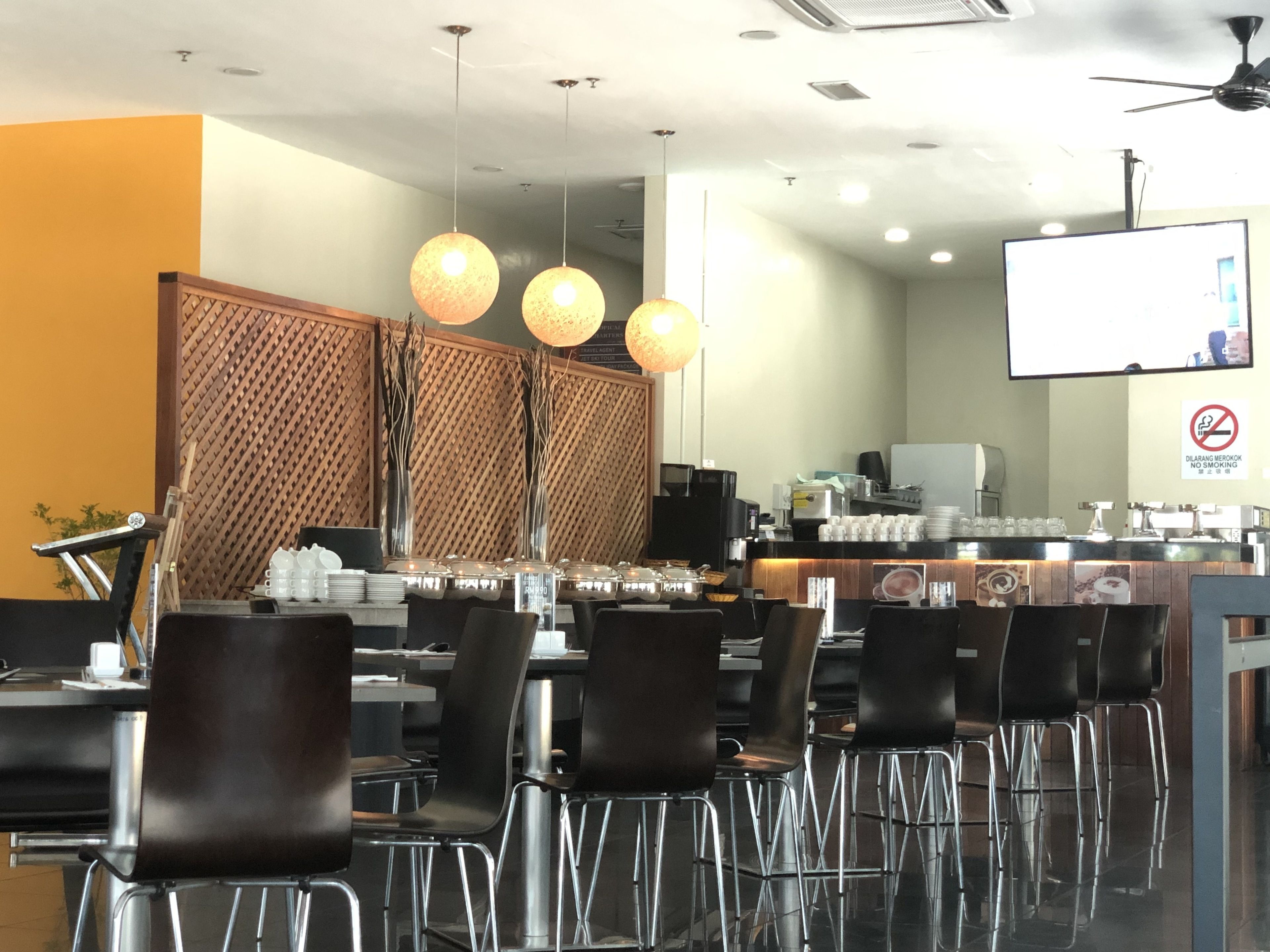 En modern restaurang med en bardisk, sittområde och en skärm där en presentation visas.