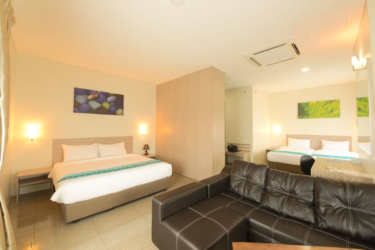 Una habitación de hotel con una cama, un sofá, una mesita de noche y un espejo.