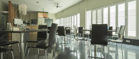 A spacious, modern restaurant with high ceilings, large windows, and a clean, minimalist interior.
