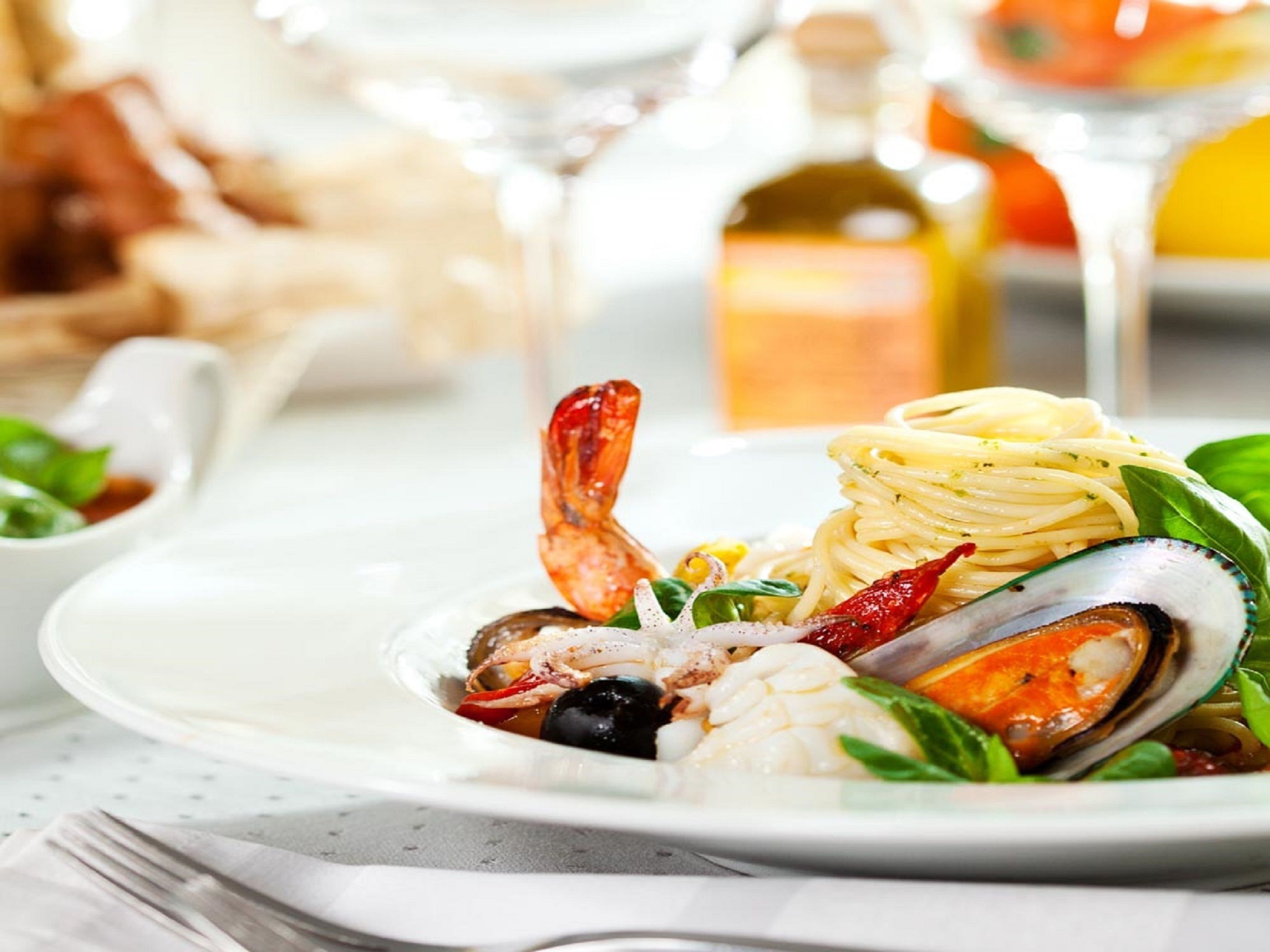 A seafood dish with pasta, shrimp, mussels, and vegetables on a plate.