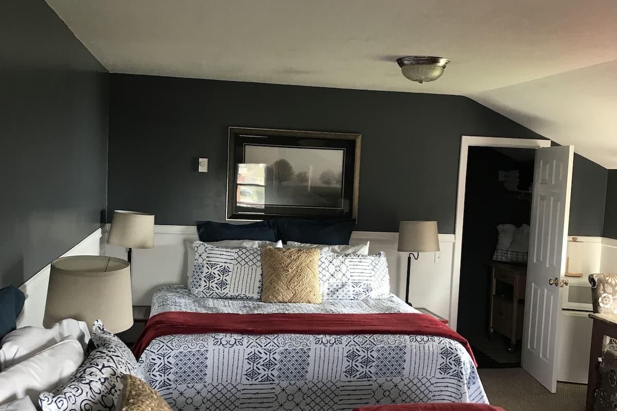 A bedroom with two beds, a large mirror, and a door leading to a bathroom.