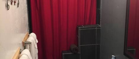 A bathroom with a red shower curtain, a white sink, and a toilet.
