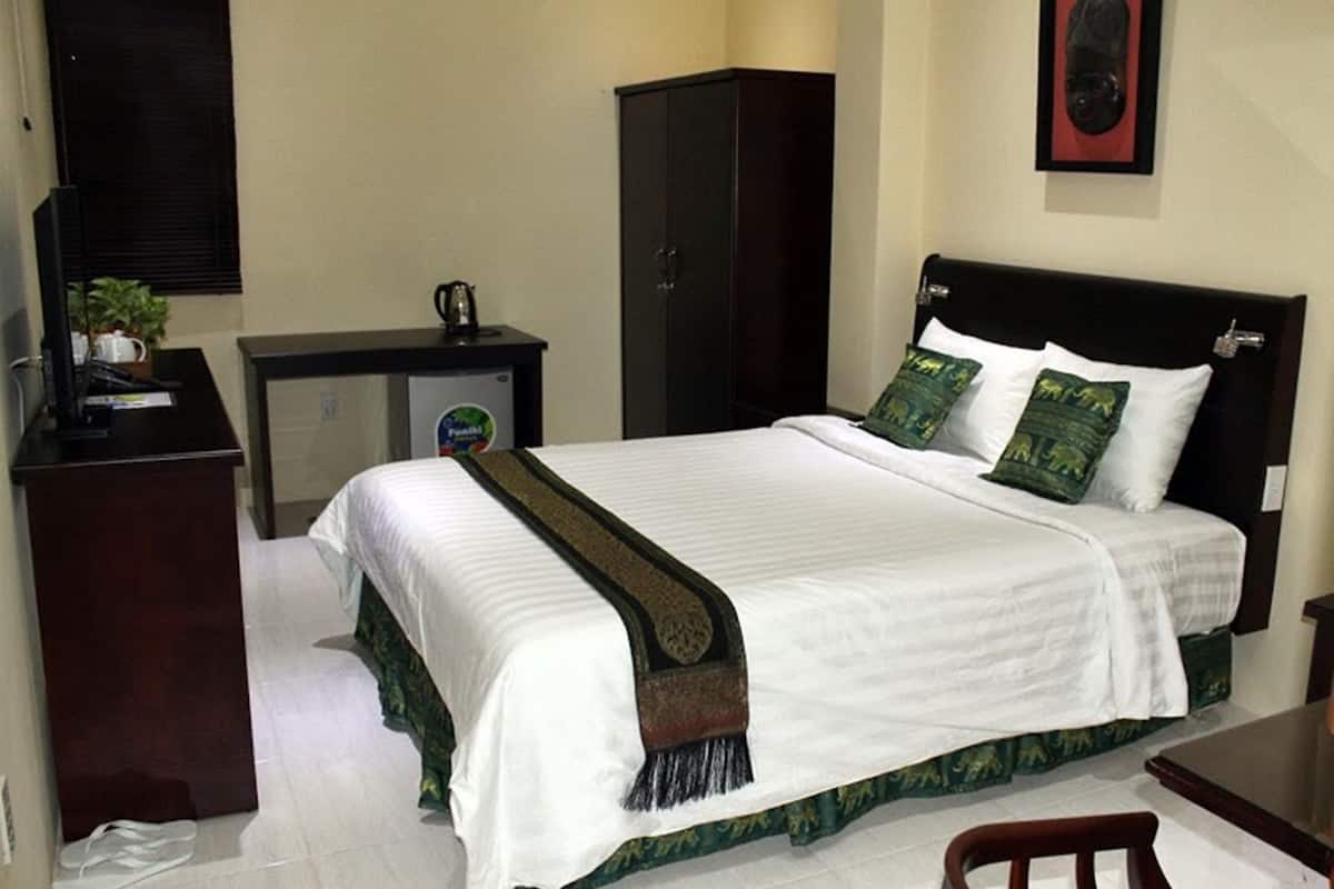 Una habitación de hotel con cama, escritorio, armario y una pequeña mesa.