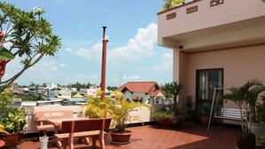 A rooftop terrace with a wooden table and benches, surrounded by potted plants. - Murray Guesthouse (Chau Doc)