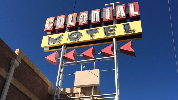 A motel sign with the words "Colonial Motel" and red arrow shapes. - Colonial Motel (Gallup)