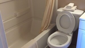 A bathroom with a bathtub, toilet, and shower curtain. - Colonial Motel (Gallup)