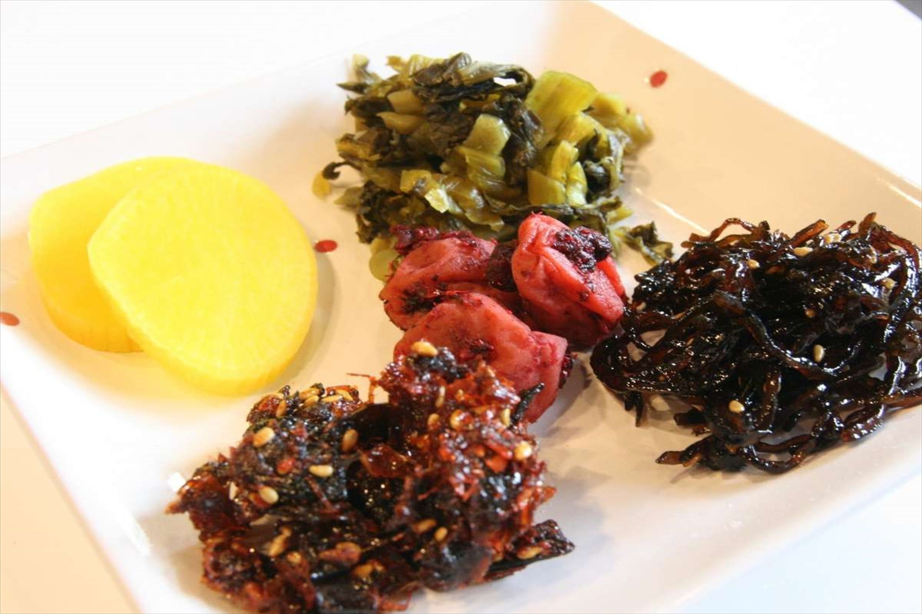 A plate with various food items including sliced potatoes, a dark sauce, and a green vegetable dish.