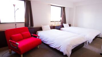 Una habitación de hotel con dos camas, un sofá rojo y una lámpara.