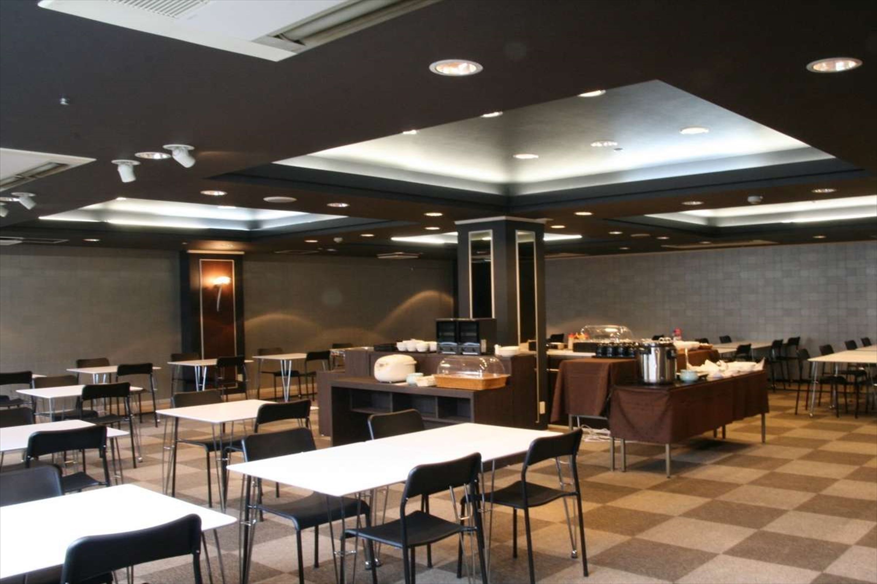 A spacious conference room with tables and chairs, a coffee station, and a large pillar.