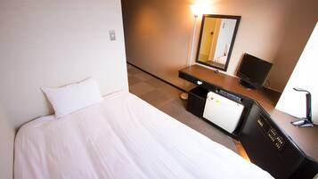 Et hotelværelse med en seng, et skrivebord med computer, et spejl og en lampe.