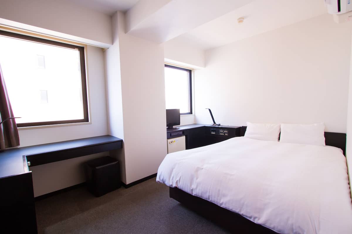 Une chambre à coucher avec un lit, un bureau et une fenêtre.