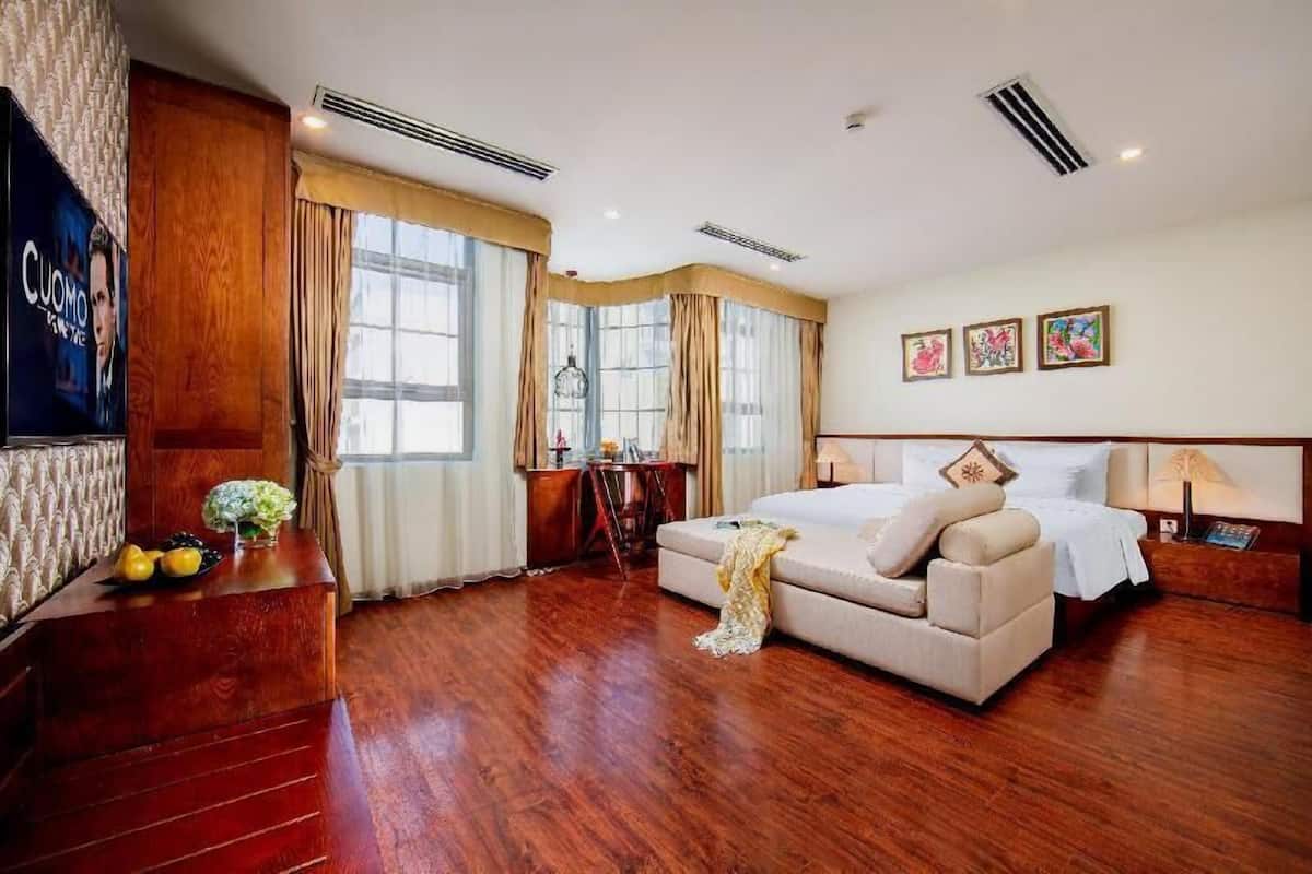 A hotel room with a bed, a desk, a chair, a TV, and a window with curtains.