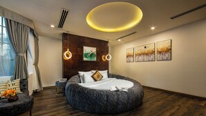 A modern bedroom with a round bed, wooden flooring, and artwork on the walls. - Midori Boutique Hotel (Hanoi)