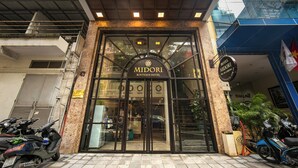 The exterior of Midori Boutique Hotel with a modern facade, large glass entrance, and a signboard displaying the hotel's name and contact information. - Midori Boutique Hotel (Hanoi)