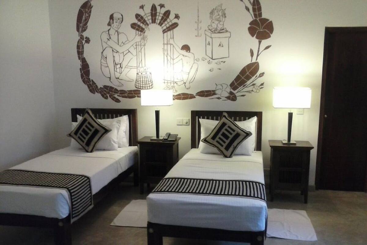 Una habitación con dos camas individuales, cada una con una almohada y una mesita de noche con lámpara.