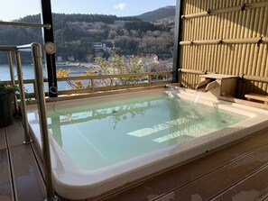 A hot tub with a wooden deck and a view of a lake and hills. - Hotel Musashiya (Hakone)