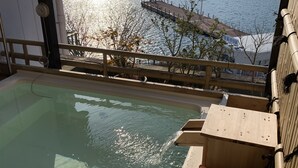 A hot spring bath with a wooden deck and a view of a lake and mountains. - Hotel Musashiya (Hakone)