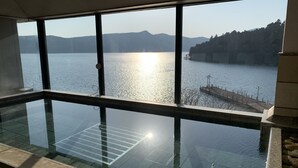 An indoor infinity pool with a clear view of a lake and distant mountains. - Hotel Musashiya (Hakone)
