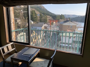 A room with a view of a traditional Japanese torii gate and buildings across a river. - Hotel Musashiya (Hakone)