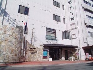 A building with a stone facade, multiple windows, and a signboard. - Hotel Musashiya (Hakone)