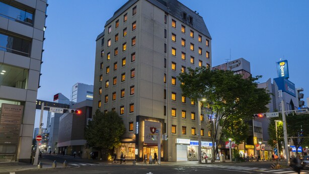 Un hotel de varios pisos con un diseño moderno, que destaca por su entrada principal y numerosas ventanas.