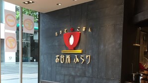 Un interior de restaurante con cabinas, mesas y una pared oscura con un logotipo.
