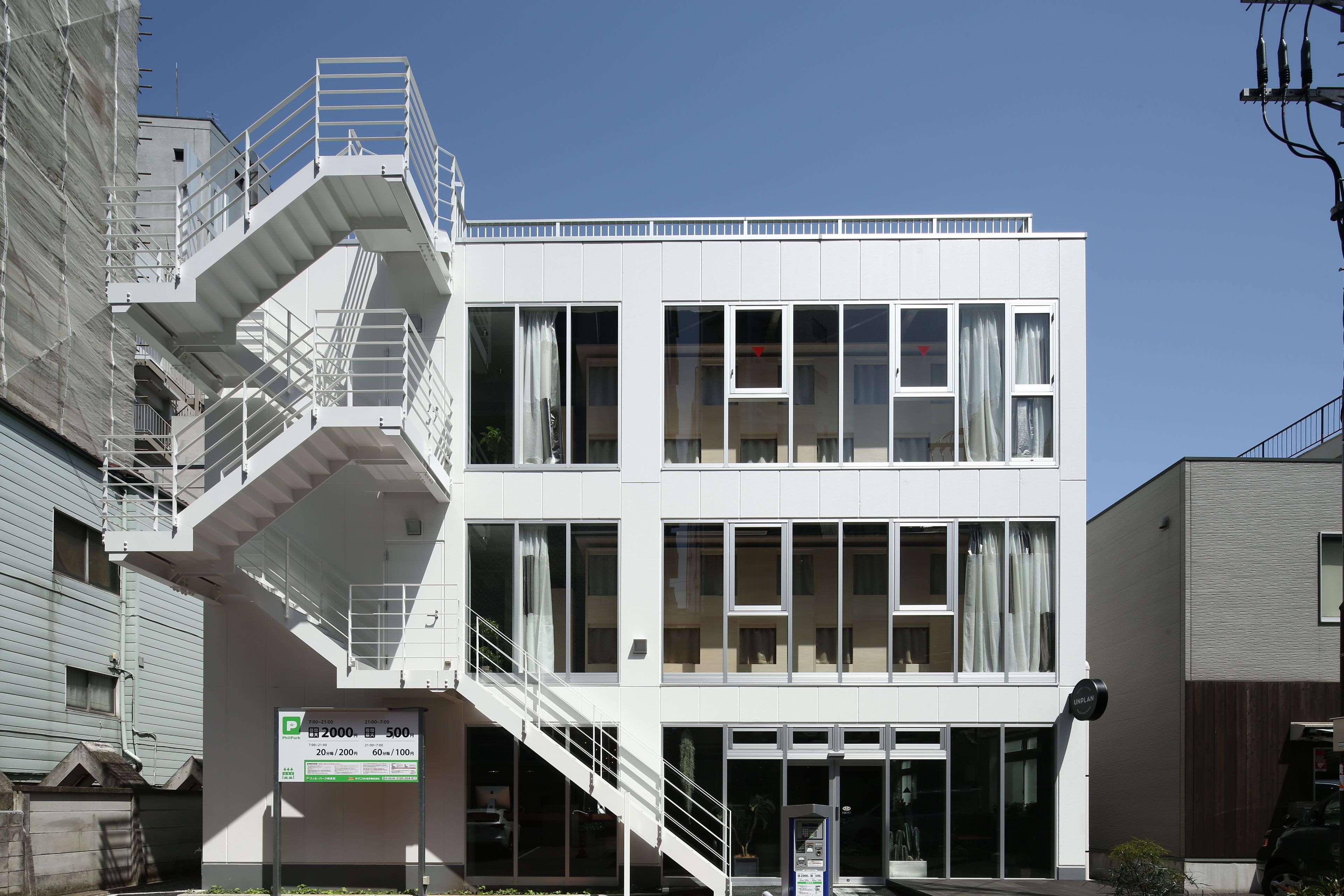 A modern building with a fire escape, multiple windows, and a parking sign indicating 2000 meters and 500 meters.