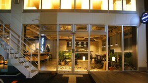 A modern building with a glass storefront, a visible staircase, and a sign reading "UNPLANNED". - UNPLAN Kagurazaka - Hostel (Tokyo)