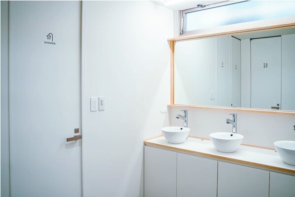 Un baño moderno con un espejo grande, dos lavamanos y una zona de ducha.