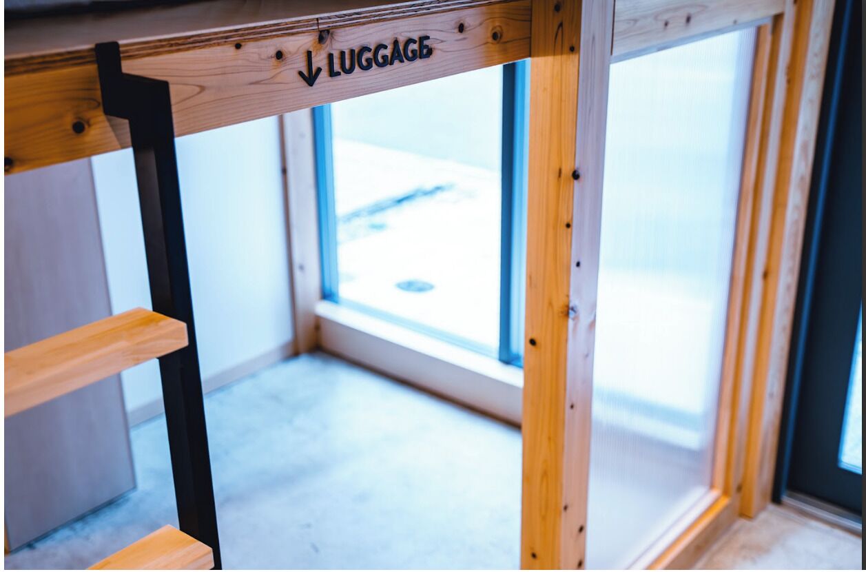 A wooden luggage rack with a sign indicating the direction to luggage.