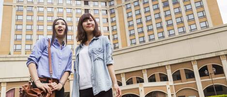 Dos personas frente a un edificio con gran cantidad de ventanas y un letrero con caracteres japoneses.