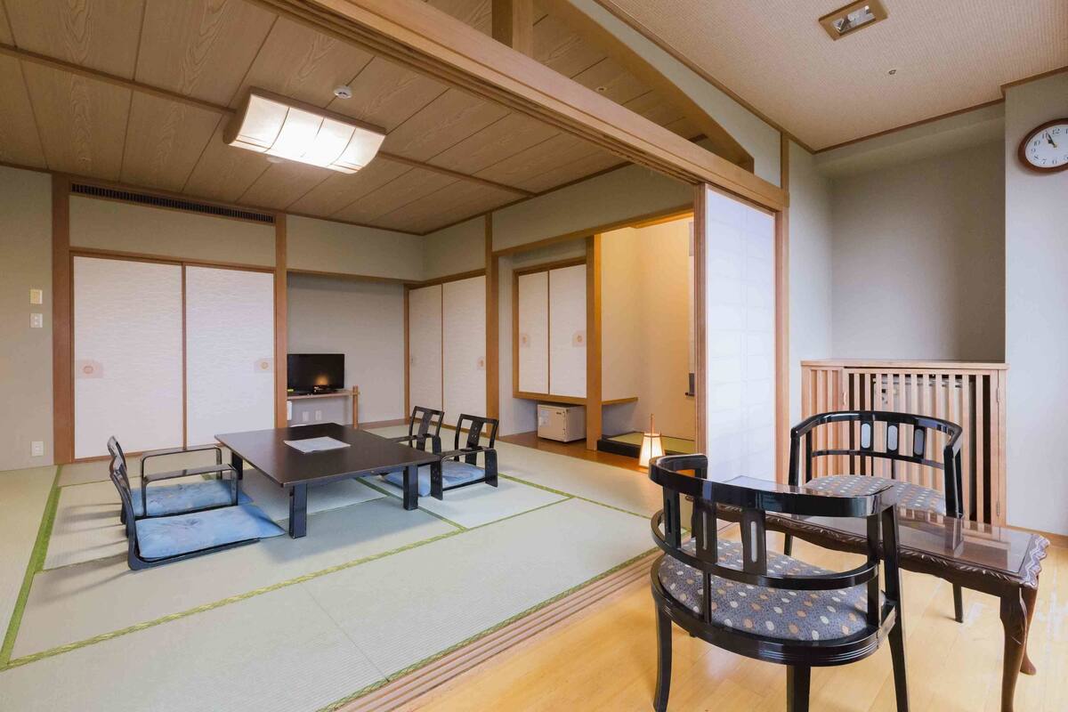 A traditional Japanese-style room with tatami flooring, a low table, and chairs.