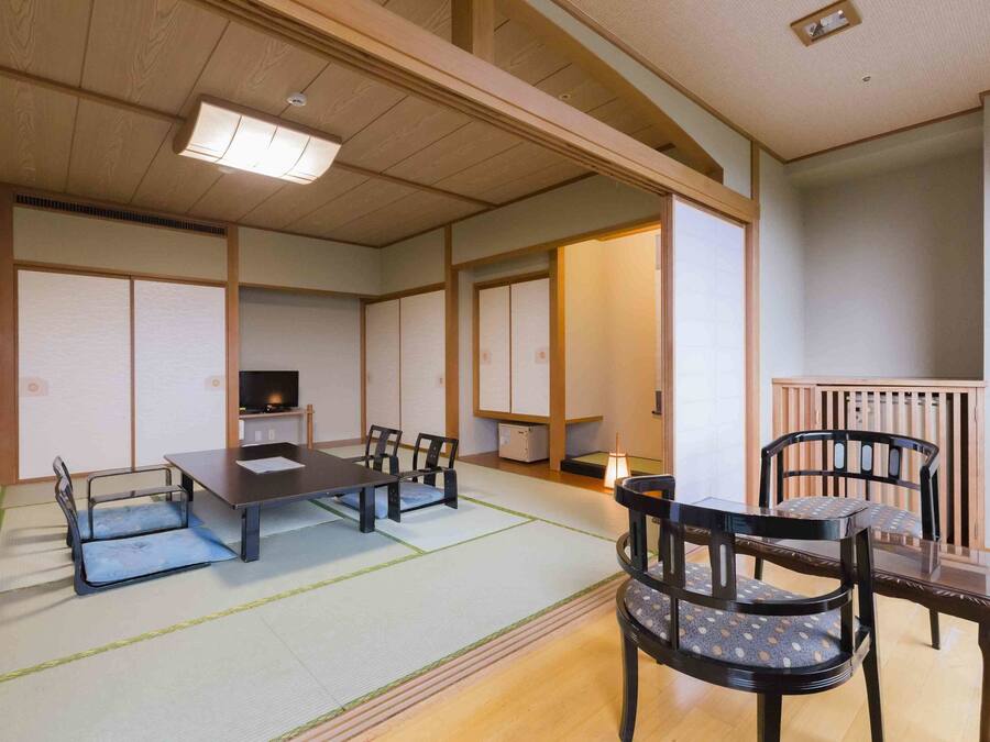 A traditional Japanese-style room with tatami flooring, a low table, and chairs.