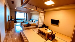 Habitación de hotel con una cama grande, un escritorio, una silla, un televisor y vistas a la ciudad.