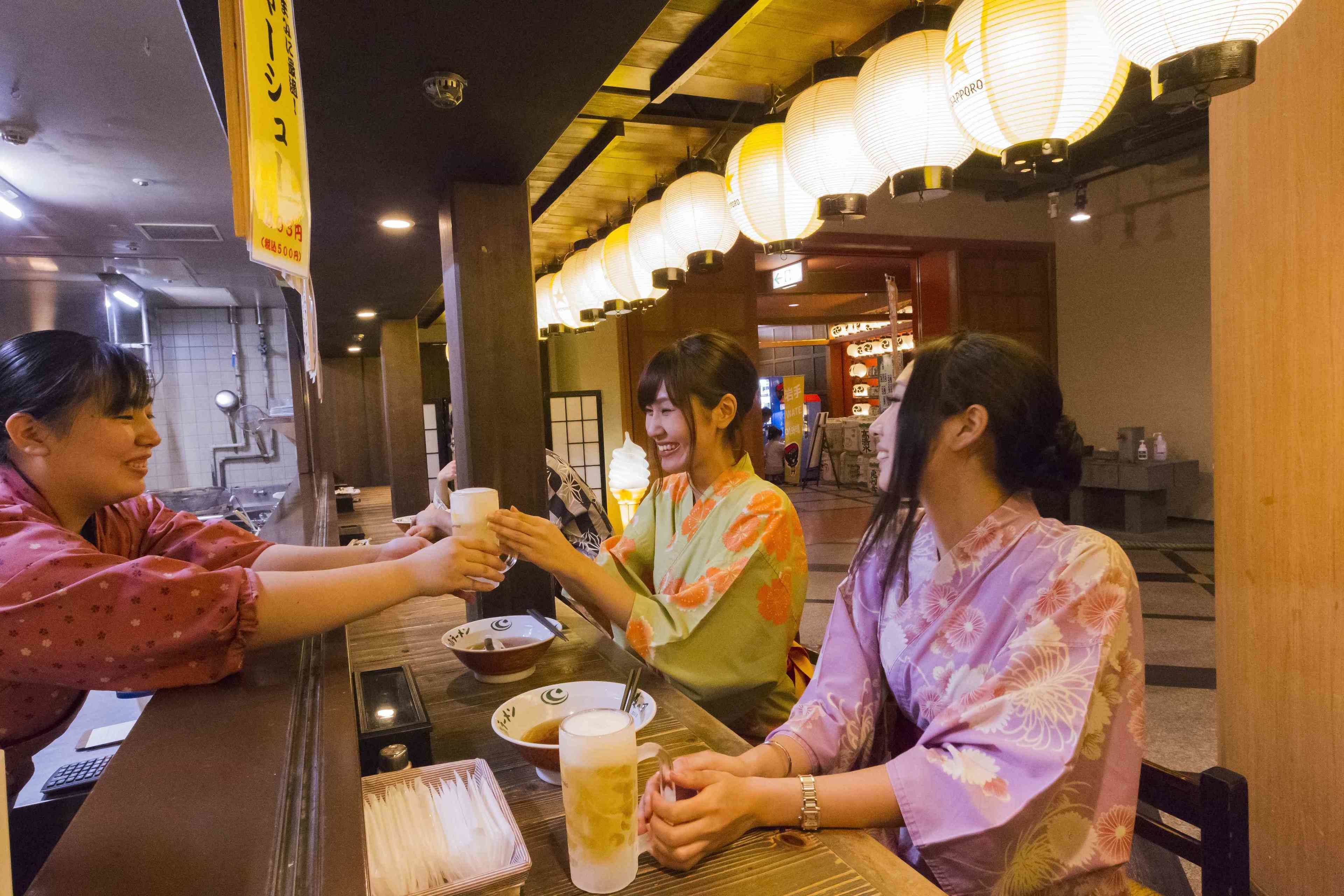 A restaurant interior with wooden tables, traditional lanterns, and Japanese-style decor.