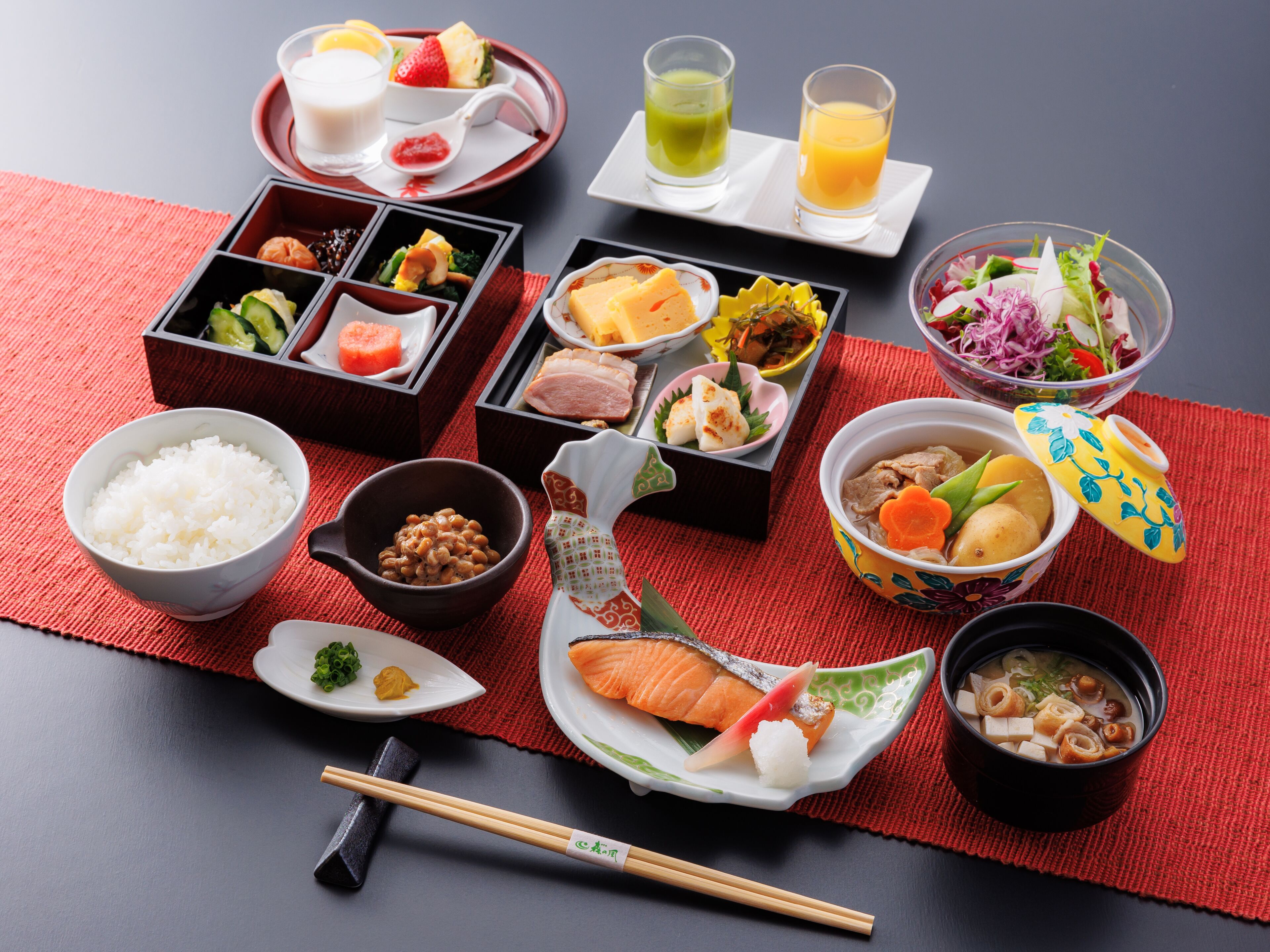 Diversos pratos japoneses dispostos sobre uma mesa, com pauzinhos e um tapete vermelho.