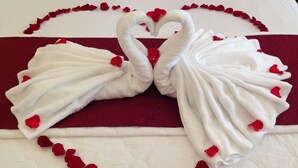Ein Bett mit einer herzförmigen Anordnung aus Handtüchern und Rosenblättern.