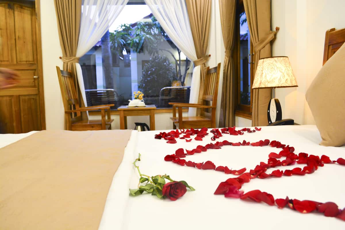 A hotel room with a bed, a table with chairs, and a window with curtains.