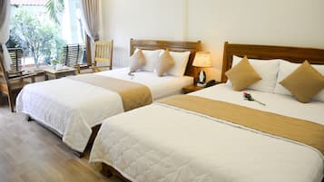 Two single beds with wooden headboards, a bedside table with a lamp, and a chair with a table.