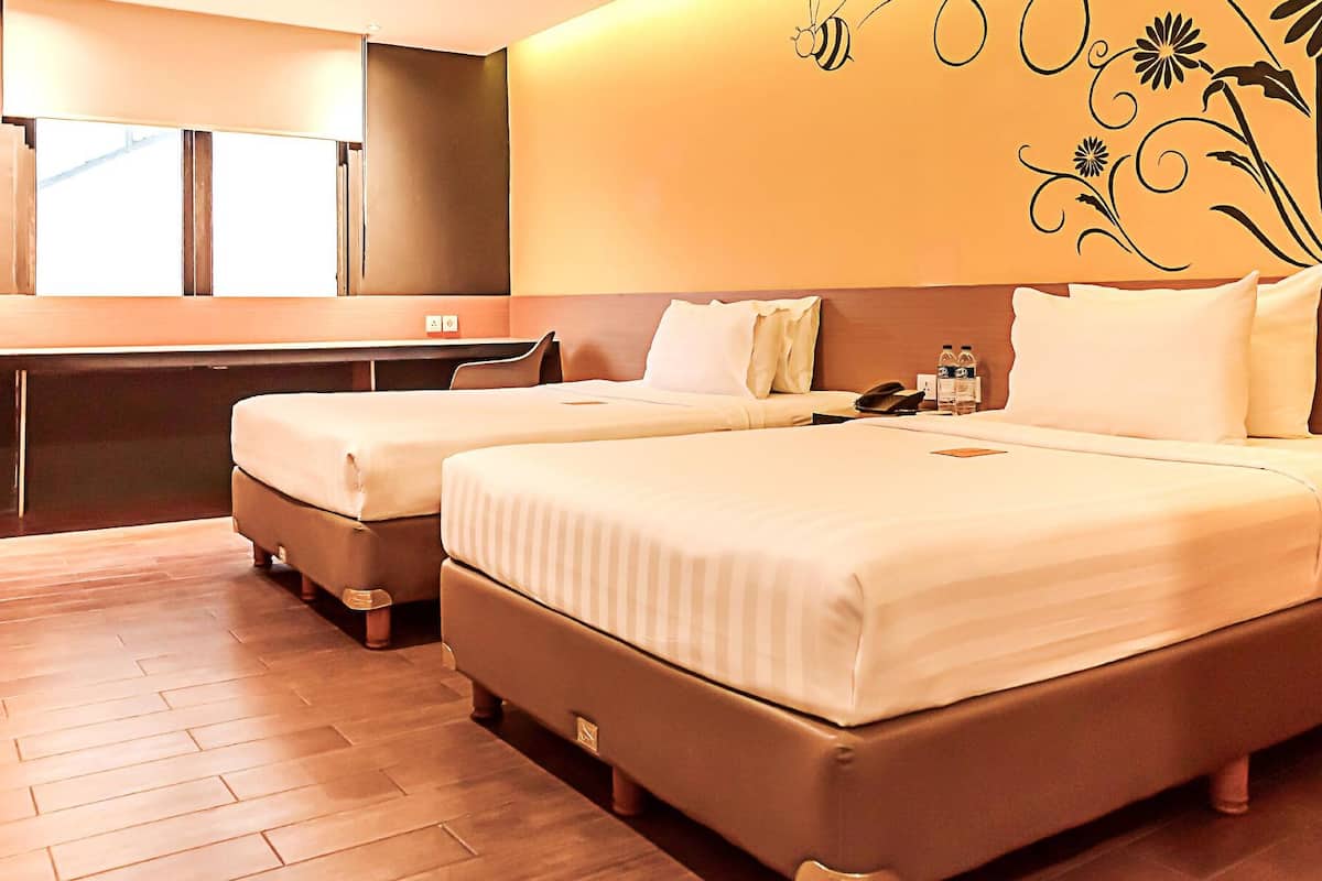 Quarto de hotel com duas camas, uma escrivaninha e um espelho.