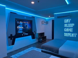 A modern bedroom with a gaming setup, a bed, and a motivational wall sign. - Yellow Bee Tangerang (Tangerang)