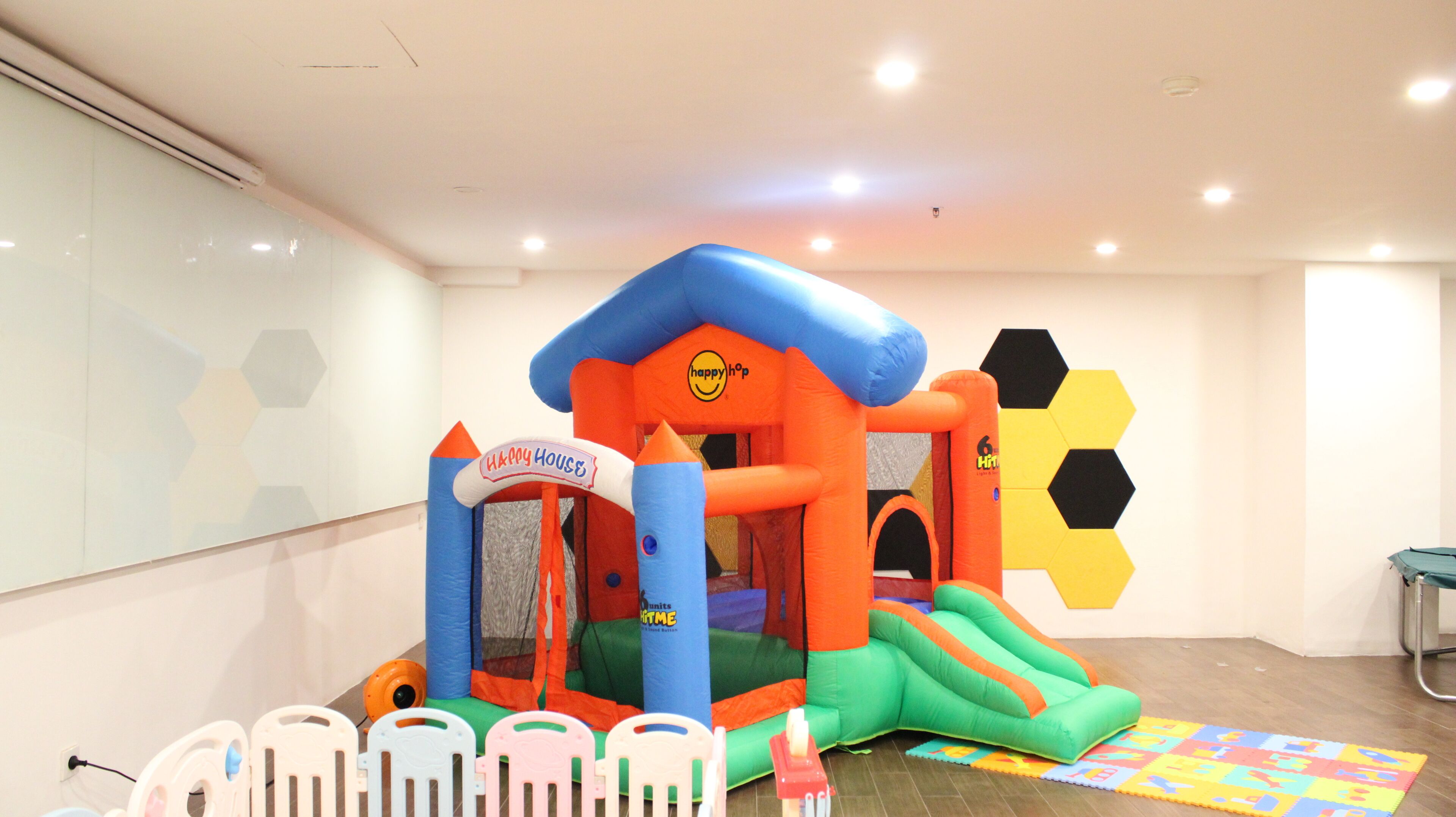Un área de juegos interior con una colorida casa inflable, un tobogán y un pequeño trampolín.